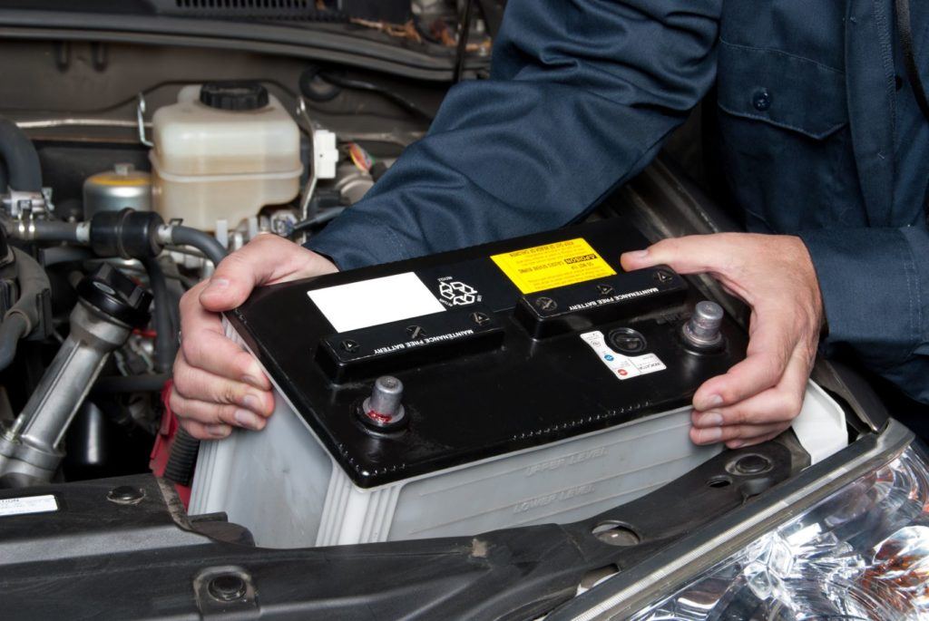 Mechanic replacing a car battery.
